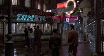 Movie still from “Streets of Fire” (1984), directed by Walter Hill – A group of people standing in front of a diner at night; Wide shot, High angle