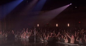 Movie still from “Streets of Fire” (1984), directed by Walter Hill – A crowd of people sitting in front of microphones; Wide shot, High angle