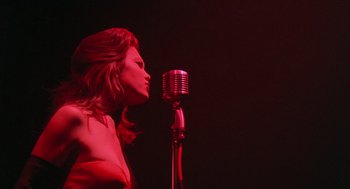 Movie still from “Streets of Fire” (1984), directed by Walter Hill – A woman standing in front of a microphone on a stage; Medium shot, Low angle