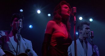 Movie still from “Streets of Fire” (1984), directed by Walter Hill – A woman singing into a microphone on a stage; Medium shot, Low angle