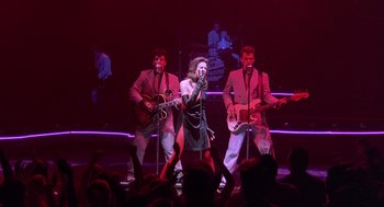 Movie still from “Streets of Fire” (1984), directed by Walter Hill – A group of people on a stage with guitars; Wide shot, Low angle