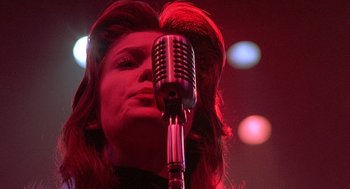 Movie still from “Streets of Fire” (1984), directed by Walter Hill – A woman with long hair standing in front of a microphone; Close Up shot, Low angle