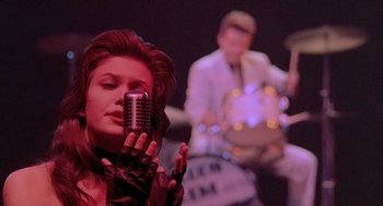 Movie still from “Streets of Fire” (1984), directed by Walter Hill – A woman holding a microphone up to her face; Medium shot, Low angle