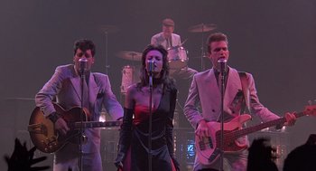 Movie still from “Streets of Fire” (1984), directed by Walter Hill – A group of people that are singing on a stage; Wide shot, Low angle
