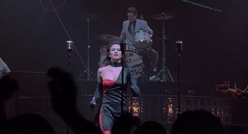 Movie still from “Streets of Fire” (1984), directed by Walter Hill – A woman standing on a stage in front of a microphone; Wide shot, Low angle
