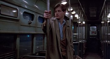 Movie still from “Streets of Fire” (1984), directed by Walter Hill – A man in a trench coat on a train; Medium shot, Low angle