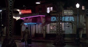 Movie still from “Streets of Fire” (1984), directed by Walter Hill – A man walking down the street in front of a building; Extreme Wide shot, High angle