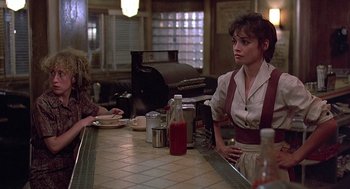 Movie still from “Streets of Fire” (1984), directed by Walter Hill – A woman sitting at a bar with a bottle of ketchup; Medium shot, Over the shoulder angle