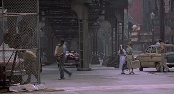 Movie still from “Streets of Fire” (1984), directed by Walter Hill – A group of people standing under a metal structure; Extreme Wide shot, High angle