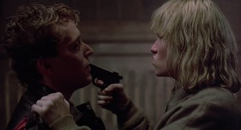 Movie still from “Streets of Fire” (1984), directed by Walter Hill – A man and a woman holding a gun in a room; Close Up shot, Over the shoulder angle