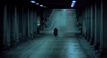 Movie still from “Streets of Fire” (1984), directed by Walter Hill – A person riding a motorcycle down a street; Wide shot, High angle
