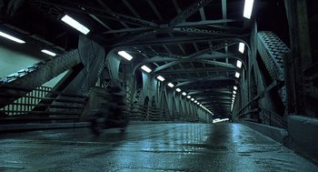 Movie still from “Streets of Fire” (1984), directed by Walter Hill – A person riding a motorcycle on a bridge; Extreme Wide shot, High angle