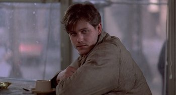 Movie still from “Streets of Fire” (1984), directed by Walter Hill – A person sitting at a table with a cup of coffee; Close Up shot, Over the shoulder angle