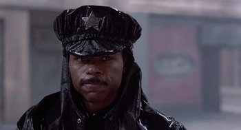 Movie still from “Streets of Fire” (1984), directed by Walter Hill – A man wearing a black police uniform and a hat; Close Up shot, Low angle