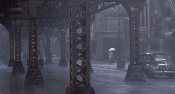 Movie still from “Streets of Fire” (1984), directed by Walter Hill – A person with an umbrella walking down a street; Extreme Wide shot, High angle