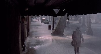 Movie still from “Streets of Fire” (1984), directed by Walter Hill – A car driving down a street in the rain; Wide shot, High angle
