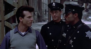 Movie still from “Streets of Fire” (1984), directed by Walter Hill – A group of men standing next to each other on a street; Medium shot, Over the shoulder angle