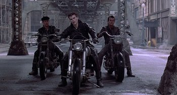 Movie still from “Streets of Fire” (1984), directed by Walter Hill – A group of men riding motorcycles on top of a road; Wide shot, Low angle