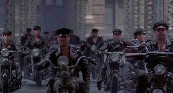 Movie still from “Streets of Fire” (1984), directed by Walter Hill – A group of men riding motorcycles down a street; Wide shot, High angle