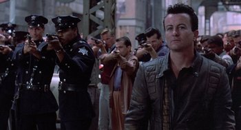 Movie still from “Streets of Fire” (1984), directed by Walter Hill – A group of people taking pictures in front of a building; Medium shot, Low angle