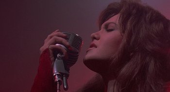 Movie still from “Streets of Fire” (1984), directed by Walter Hill – A woman holding a microphone up to her face; Close Up shot, Low angle