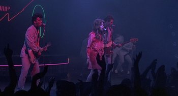 Movie still from “Streets of Fire” (1984), directed by Walter Hill – A group of people on a stage singing; Wide shot, Overhead angle