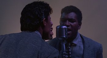 Movie still from “Streets of Fire” (1984), directed by Walter Hill – Two men are singing into a vintage microphone; Close Up shot, Low angle
