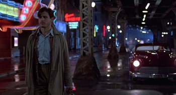 Movie still from “Streets of Fire” (1984), directed by Walter Hill – A man walking down a street at night; Wide shot, Over the shoulder angle