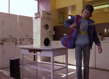 A young man is walking in a room with appliances