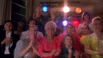 Movie still from “Strictly Ballroom” (1992), directed by Baz Luhrmann – A group of people in a room with lights on; Wide shot, Low angle