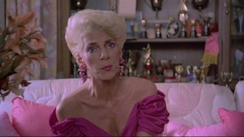 Movie still from “Strictly Ballroom” (1992), directed by Baz Luhrmann – An older woman in a pink dress sitting on a couch; Close Up shot, Over the shoulder angle