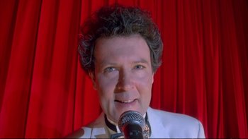 Movie still from “Strictly Ballroom” (1992), directed by Baz Luhrmann – A person holding a microphone; Close Up shot, Low angle