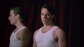 Movie still from “Strictly Ballroom” (1992), directed by Baz Luhrmann – A man in a white tank top looking at himself in the mirror; Medium shot, Low angle