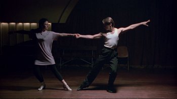 Movie still from “Strictly Ballroom” (1992), directed by Baz Luhrmann – A man and a woman are dancing on a stage; Wide shot, Low angle