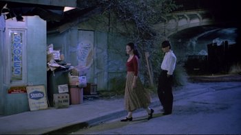 Movie still from “Strictly Ballroom” (1992), directed by Baz Luhrmann – A woman and a man walking down a street; Wide shot, High angle