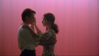 Movie still from “Strictly Ballroom” (1992), directed by Baz Luhrmann – A man and a woman standing next to each other in front of a pink wall; Medium shot, Low angle