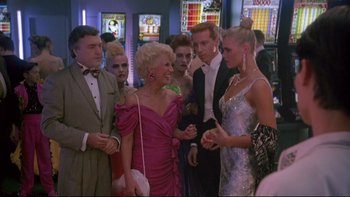 Movie still from “Strictly Ballroom” (1992), directed by Baz Luhrmann – A group of people standing around each other at a party; Medium shot, Over the shoulder angle