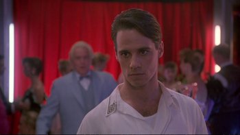 Movie still from “Strictly Ballroom” (1992), directed by Baz Luhrmann – A man in white shirt standing in front of a group of people; Close Up shot, Low angle