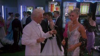 Movie still from “Strictly Ballroom” (1992), directed by Baz Luhrmann – A man and a woman are drinking champagne at an event; Medium shot, Over the shoulder angle