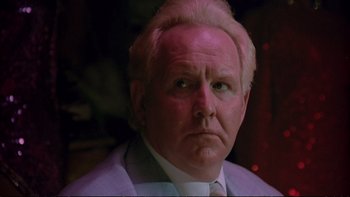 Movie still from “Strictly Ballroom” (1992), directed by Baz Luhrmann – An older man in a suit and tie looking at the camera; Close Up shot, Low angle