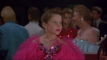 Movie still from “Strictly Ballroom” (1992), directed by Baz Luhrmann – A young girl in a pink dress with feathers on her dress; Medium shot, Over the shoulder angle