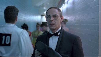 Movie still from “Strictly Ballroom” (1992), directed by Baz Luhrmann – A man in a tuxedo holding a tie in a hallway; Close Up shot, Low angle