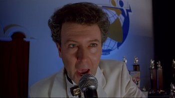 Movie still from “Strictly Ballroom” (1992), directed by Baz Luhrmann – A man in a white suit is singing into a microphone; Close Up shot, Low angle