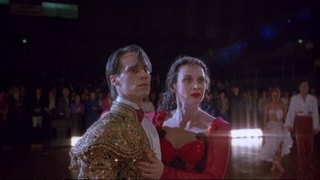Movie still from “Strictly Ballroom” (1992), directed by Baz Luhrmann – A man and a woman are posing for a picture in front of an audience; Medium shot, Low angle