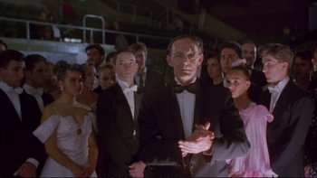 Movie still from “Strictly Ballroom” (1992), directed by Baz Luhrmann – A group of people standing in a crowd wearing tuxedos and bow ties; Medium shot, Low angle