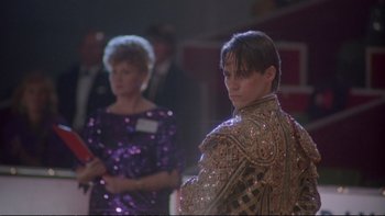 Movie still from “Strictly Ballroom” (1992), directed by Baz Luhrmann – A man in a suit standing next to a woman in a purple dress; Medium shot, Low angle