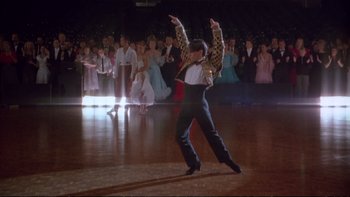 Movie still from “Strictly Ballroom” (1992), directed by Baz Luhrmann – A man is dancing on a dance floor in front of a group of people; Wide shot, Low angle