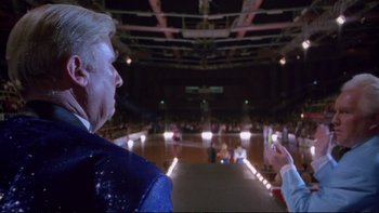 Movie still from “Strictly Ballroom” (1992), directed by Baz Luhrmann – A person taking a picture of a man in a crowd; Medium shot, Low angle