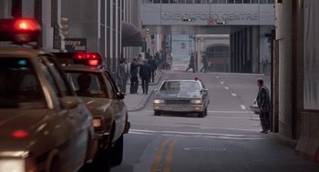 Movie still from “Striking Distance” (1993), directed by Rowdy Herrington – A car is driving down the street in the city; Extreme Wide shot, Over the shoulder angle