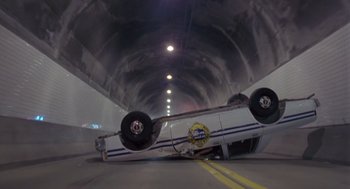 Movie still from “Striking Distance” (1993), directed by Rowdy Herrington – A car that is upside down in the middle of a tunnel; Wide shot, Low angle